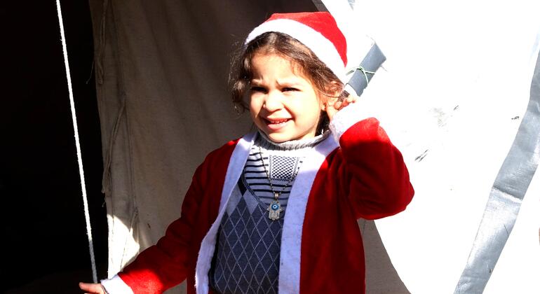 A young Palestinian girl wearing a Santa Claus outfit, stands in front of tents belonging to displaced families in northern Gaza City.